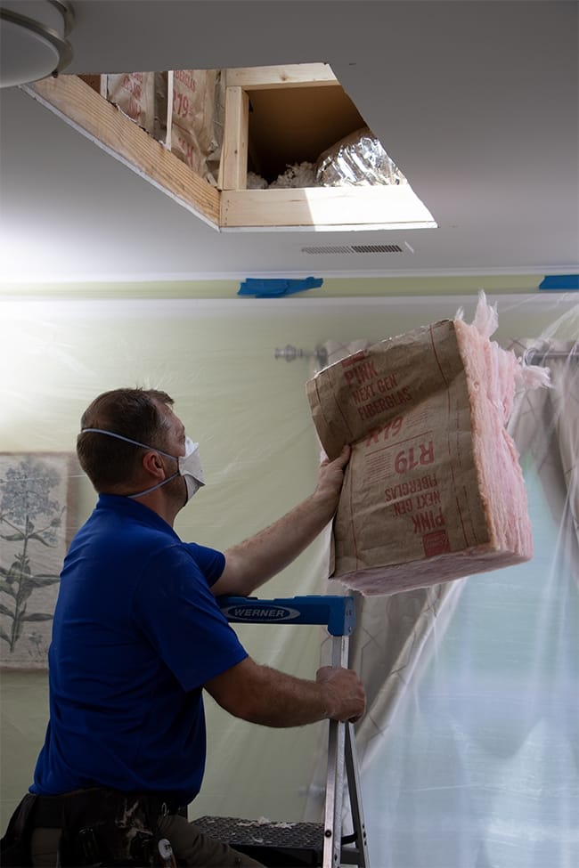 A man installing insulation in a skylight light shaft