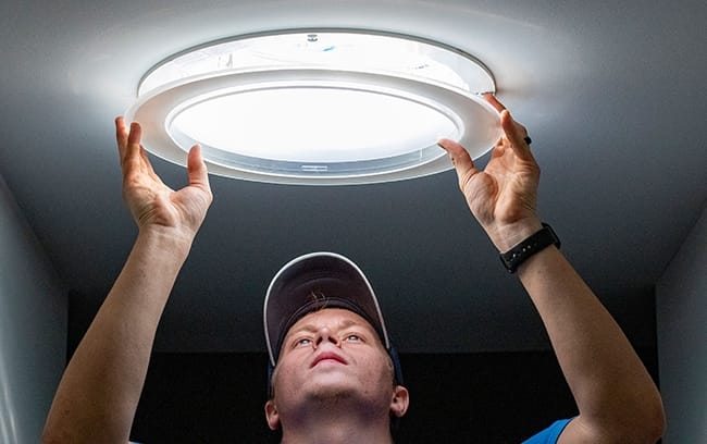 A man installs the ceiling diffuser on a Sun Tunnel skylight