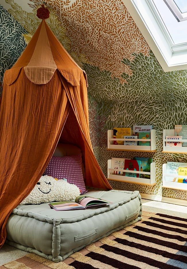 A reading nook consisting of a rust colored hanging canopy over a cushion