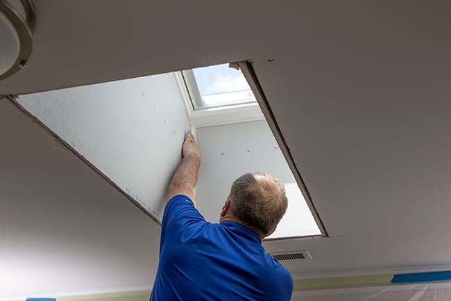 A skylight installer adds trim pieces to the inside of the light shaft