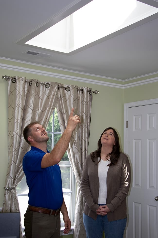 A skylight installer explains how the skylight works to a homeowner
