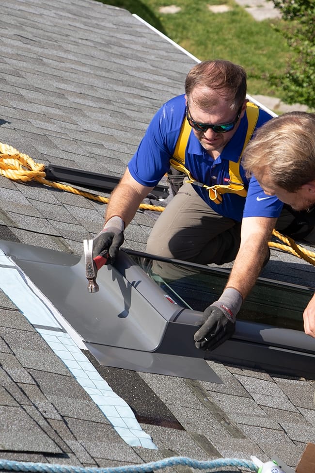 A skylight installer nails flashing in place