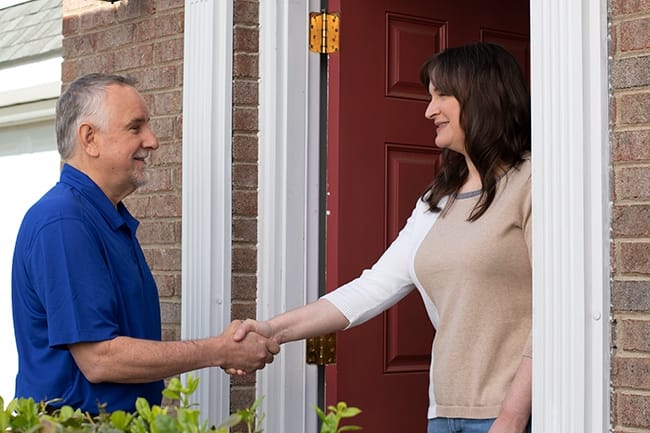 A skylight salesman greets at homeowner at the front door