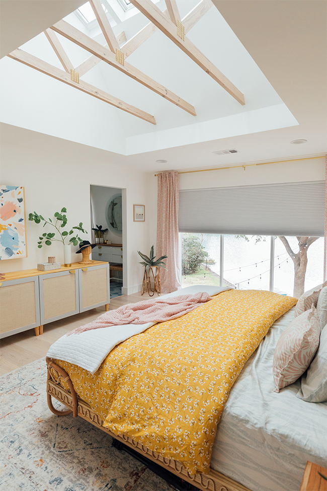 Bedroom with three skylights exposed trusses yellow and pink color scheme