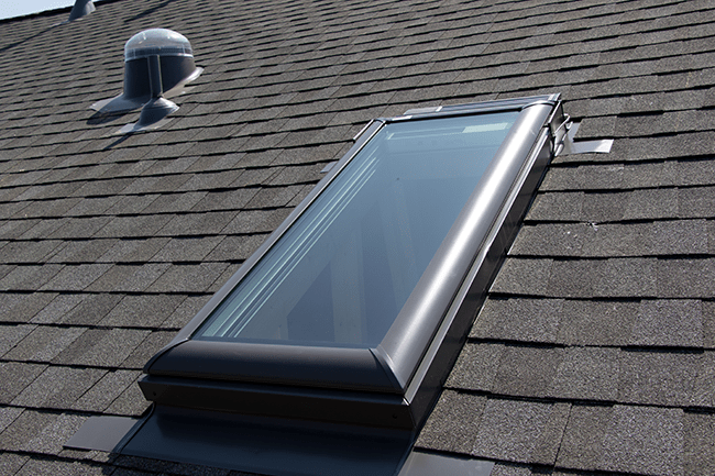 Closeup photo of a sklight on a grey shingle roof