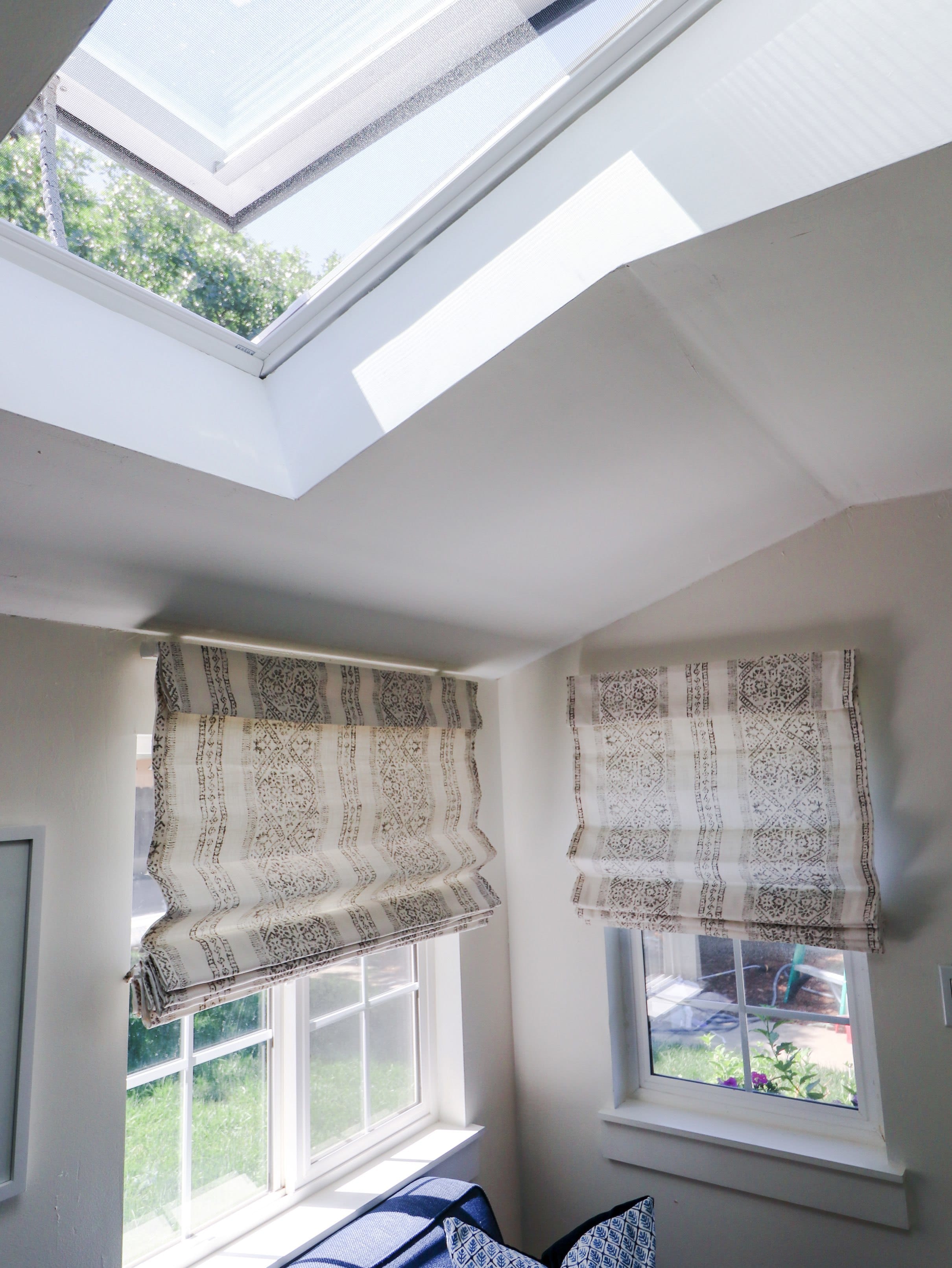 open skylight over two windows with roman shades