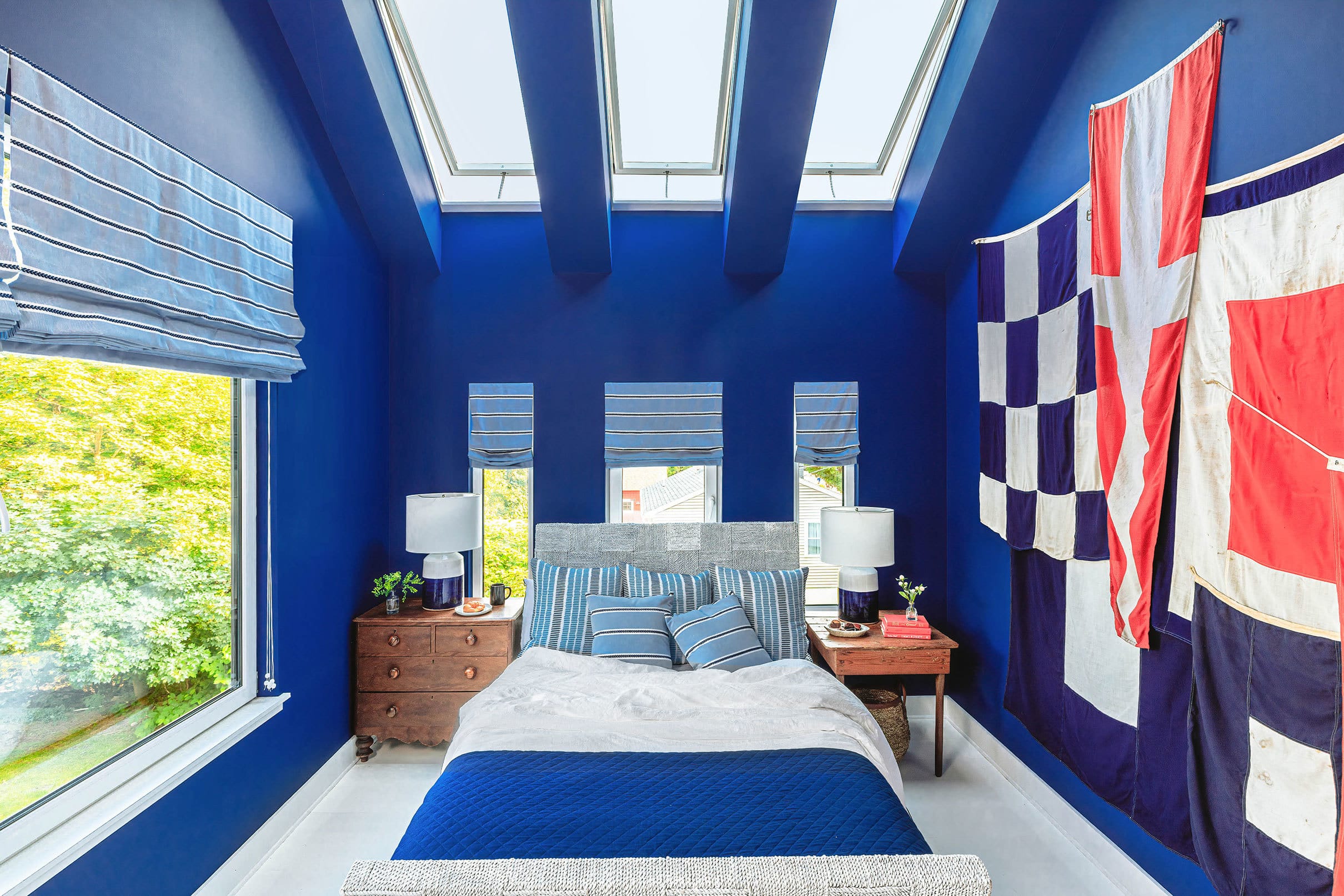 open skylights bring light into a blue bedroom with flags