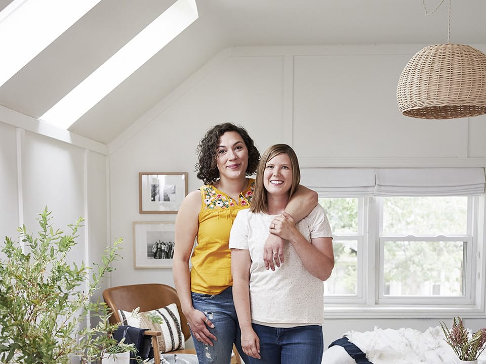 mom dad and infant sitting on a blue couch under a skylight in a living room