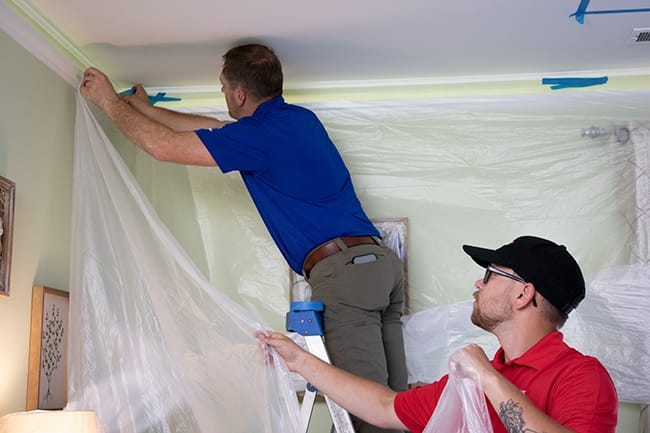 Skylight installers hang protective sheeting over walls