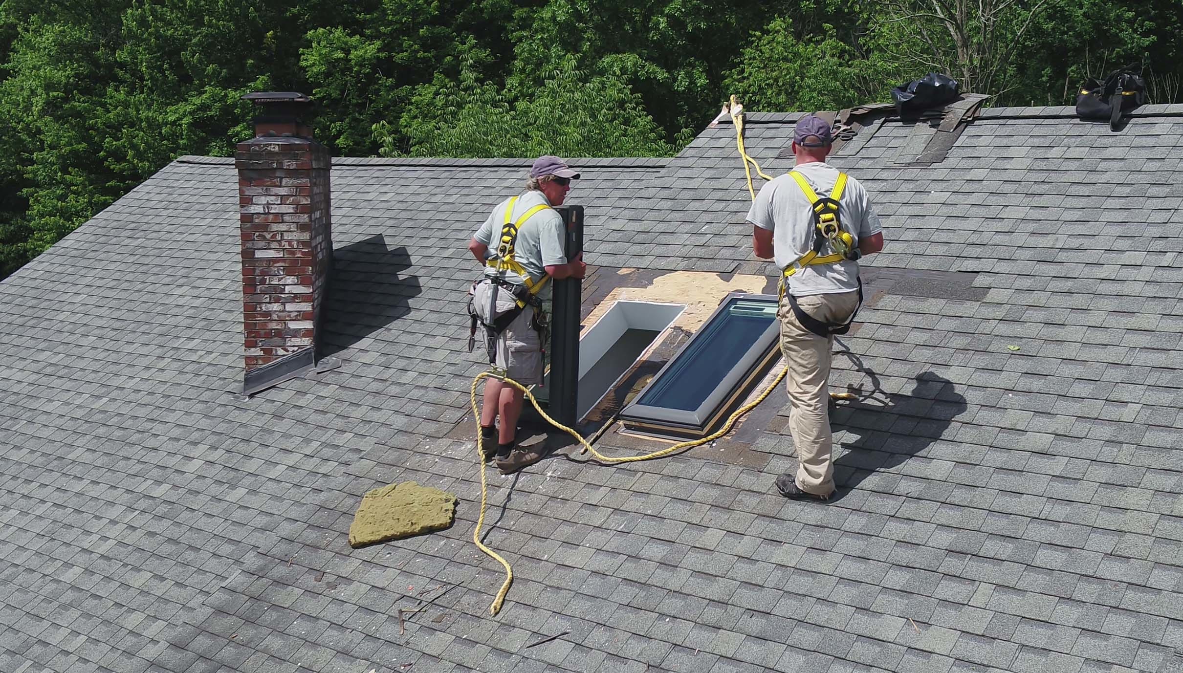 Skylight installers on a roof installing two skylights