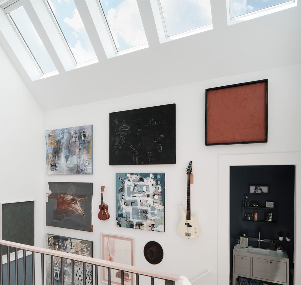 Skylights in a stairwell brighten a gallery wall lining the stairs