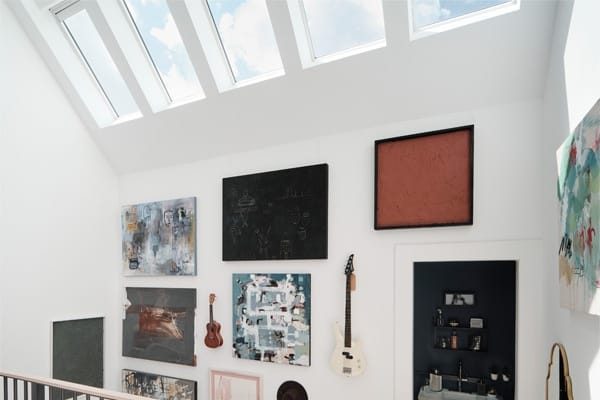 Skylights brighten a stairwell with a gallery wall TMB