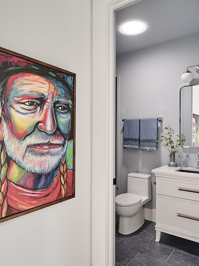 Sun Tunnel brightens light gray bathroom flanked by a portrait of Willie Nelson