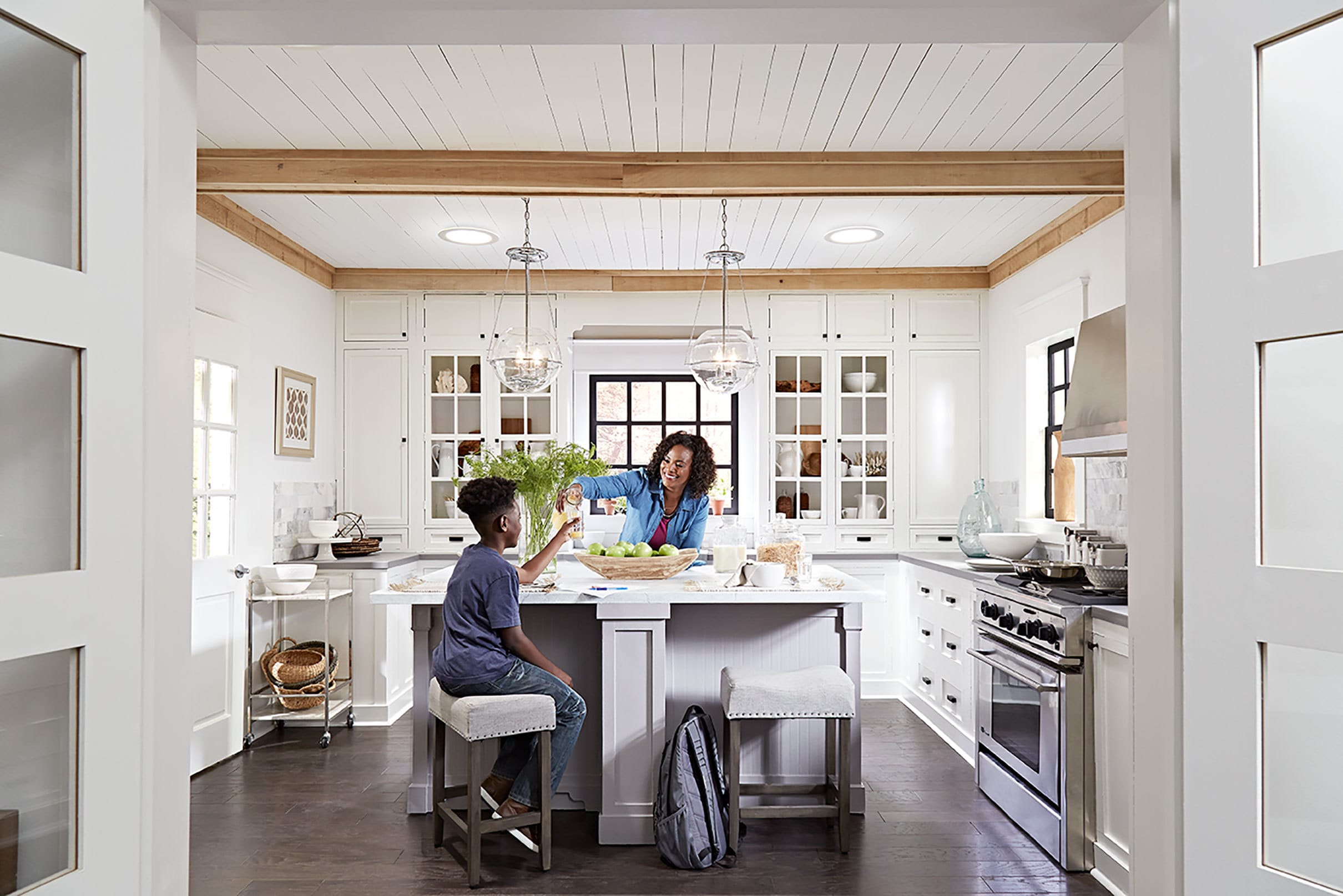 Two Sun tunnel skylights brighten a white and natural wood kitchen