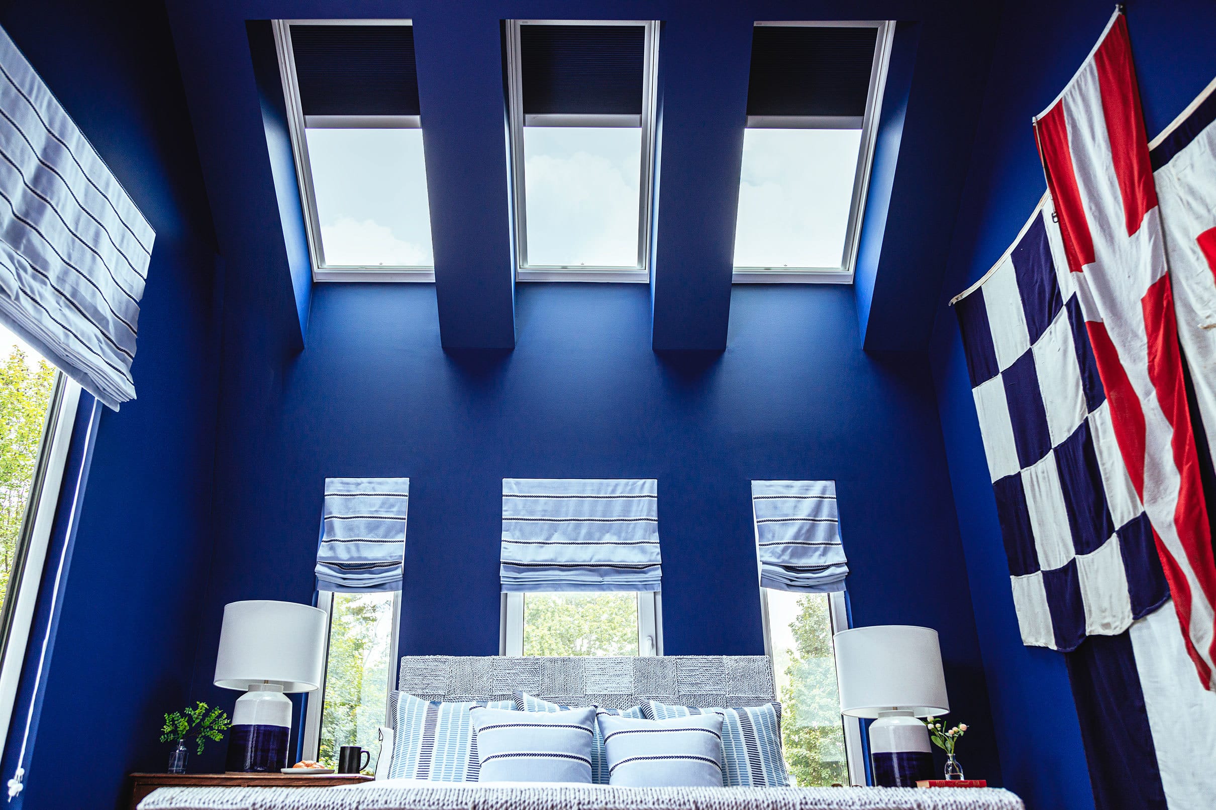 blue bedroom with three skylights and windows with blue shades