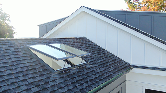 Two open skylights on black shingle roof