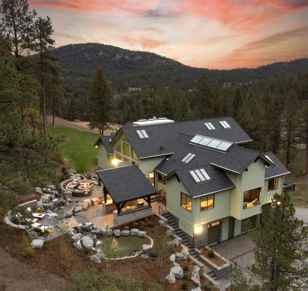 a birds eye view of a mountain home with green siding and 16 skylights in the roof