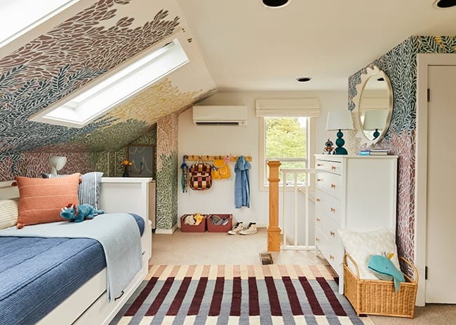 A colorful childrens bedroom with skylights a trundle bed and a striped rug