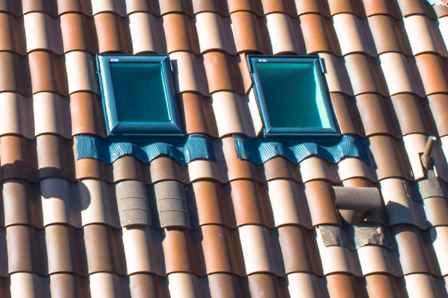 Closeup of two skylights on a barrel tile roof