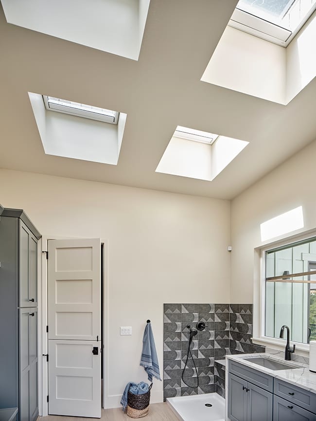 Four skylights brighten a cream colored mud room with a dog washing station