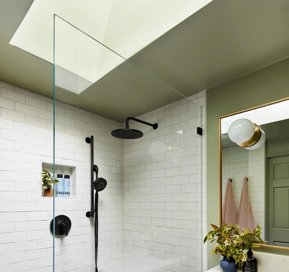 Light green bathroom with a skylight brightening the shower and vanity.
