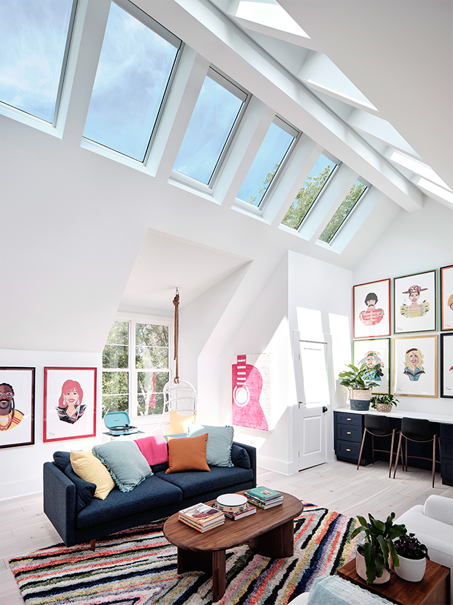 Living room with portraits brightened by roof ridge skylights