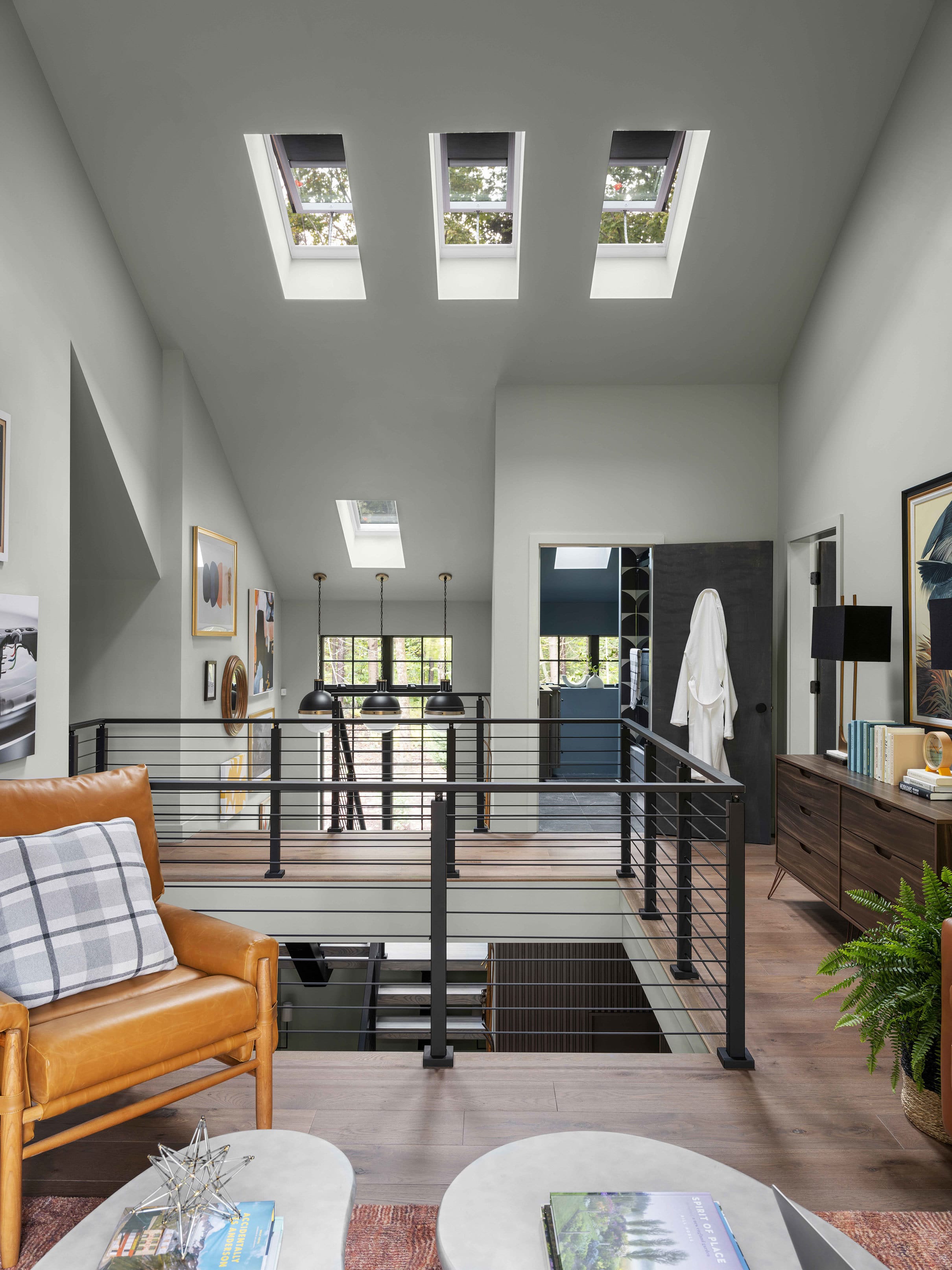 A loft with three skylights over a stairwell with wood floors and white walls