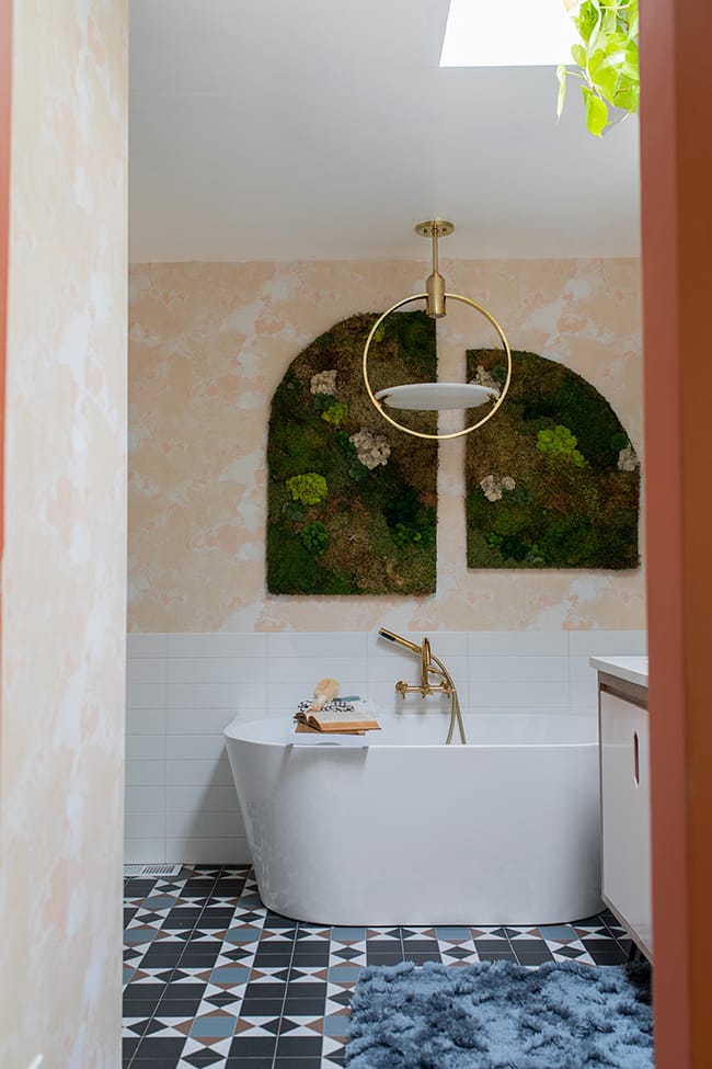 Looking through the door into a bathroom with a skylight and moss art wall hanging