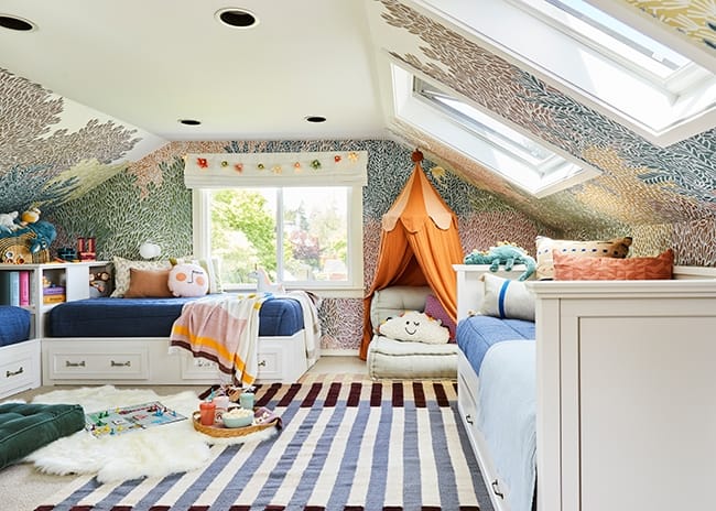Skylights brighten a colorful chidlrens bedroom with three beds and a striped rug