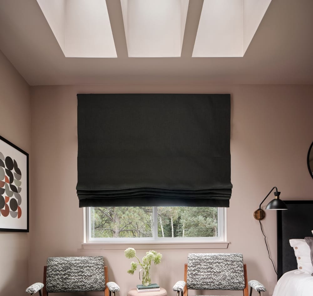 Three skylights brighten a bedroom with pink walls and gray furniture