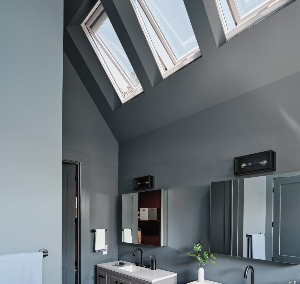 Three skylights over a double vanity brighten a bathroom painted blue