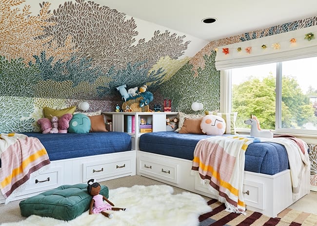 Twin beds aligned along walls in a corner of a colorful childrens bedroom