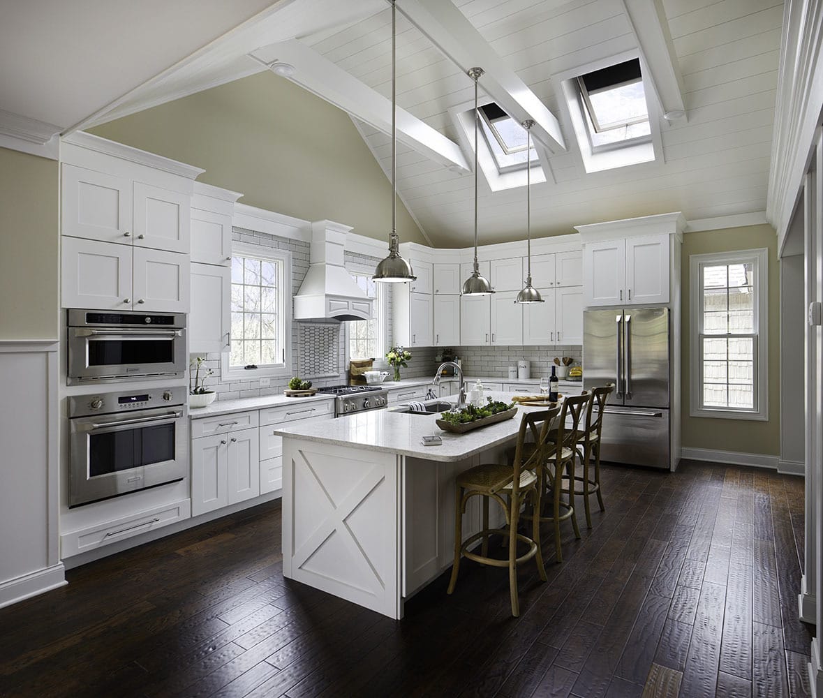 Two open skylights bring light into a large light green kitchen with white cabinetry