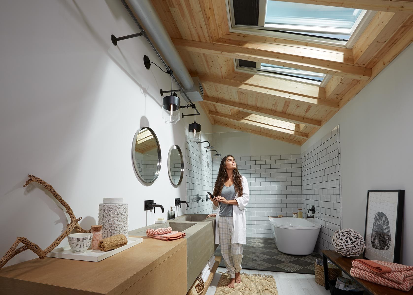 Woman looks up at three skylights in a narrow white bathroom