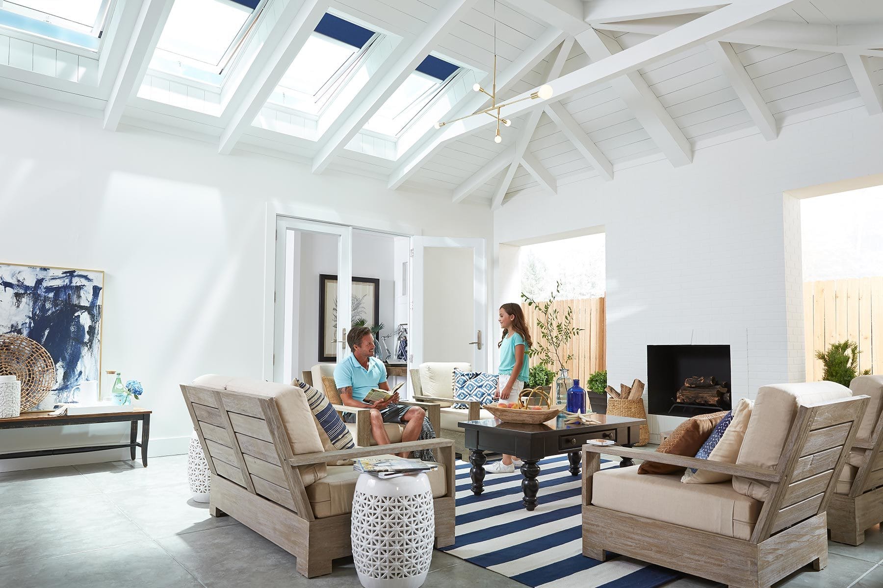 Father and daughter sitting in a white and blue living room with four skylights