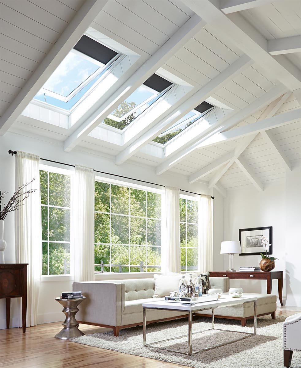 White living room with large windows and three open skylights on a vaulted ceiling